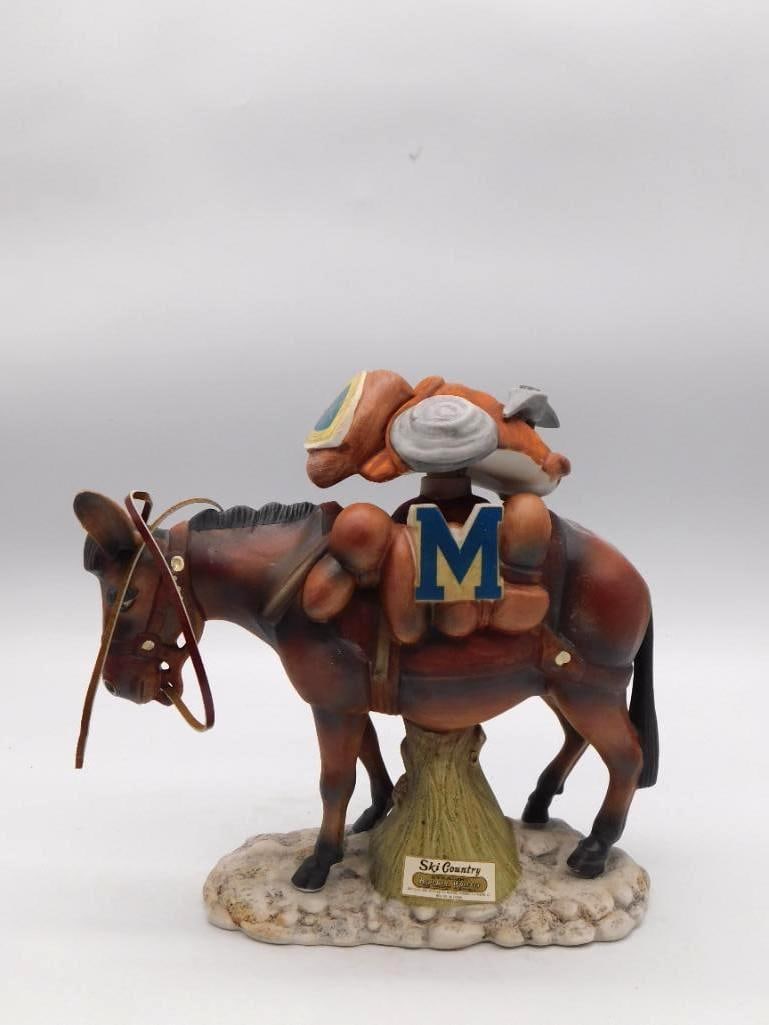 Ski Country Pack Mule M Mascot Porcelain: A hand-painted Ski Country porcelain decanter modeled as a loaded pack mule wearing an "M" saddle blanket, likely a Montana or collegiate tie-in, set on a rocky base and retaining its original paper l