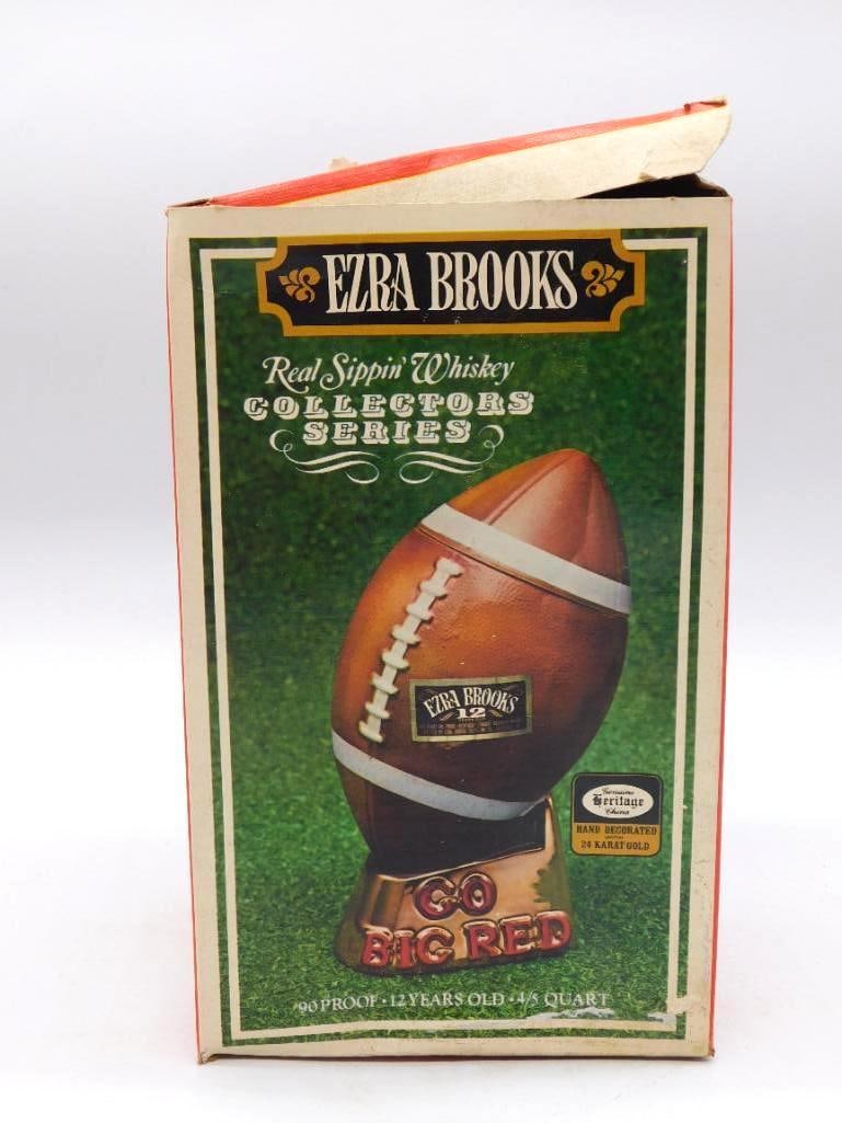 Ezra Brooks Nebraska Go Big Red Football: An Ezra Brooks decanter shaped as a football and lettered Go Big Red for Nebraska, set upon a gold-decorated base. From the Real Sippin' Whiskey Collectors Series, 12 Years Old, 90 Proof. This is the