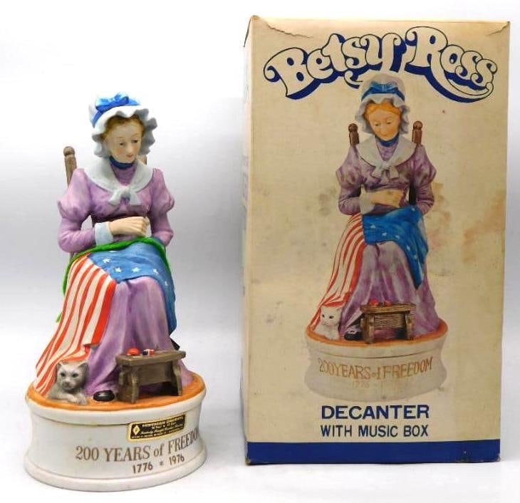 Hoffman Betsy Ross 200 Years of Freedom: A Hoffman Original decanter modeled as Betsy Ross at her chair, the flag across her lap and a kitten at her feet. The bisque is handsomely painted, and the little sewing table rewards a close look.