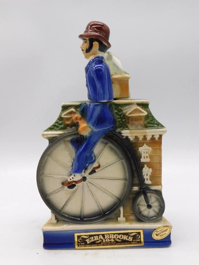 Ezra Brooks Heritage China Penny: An Ezra Brooks Heritage China decanter modeled as a Victorian gentleman astride a penny-farthing high-wheel bicycle, a townhouse facade rising behind him. A spirited bit of mold work, and the painter