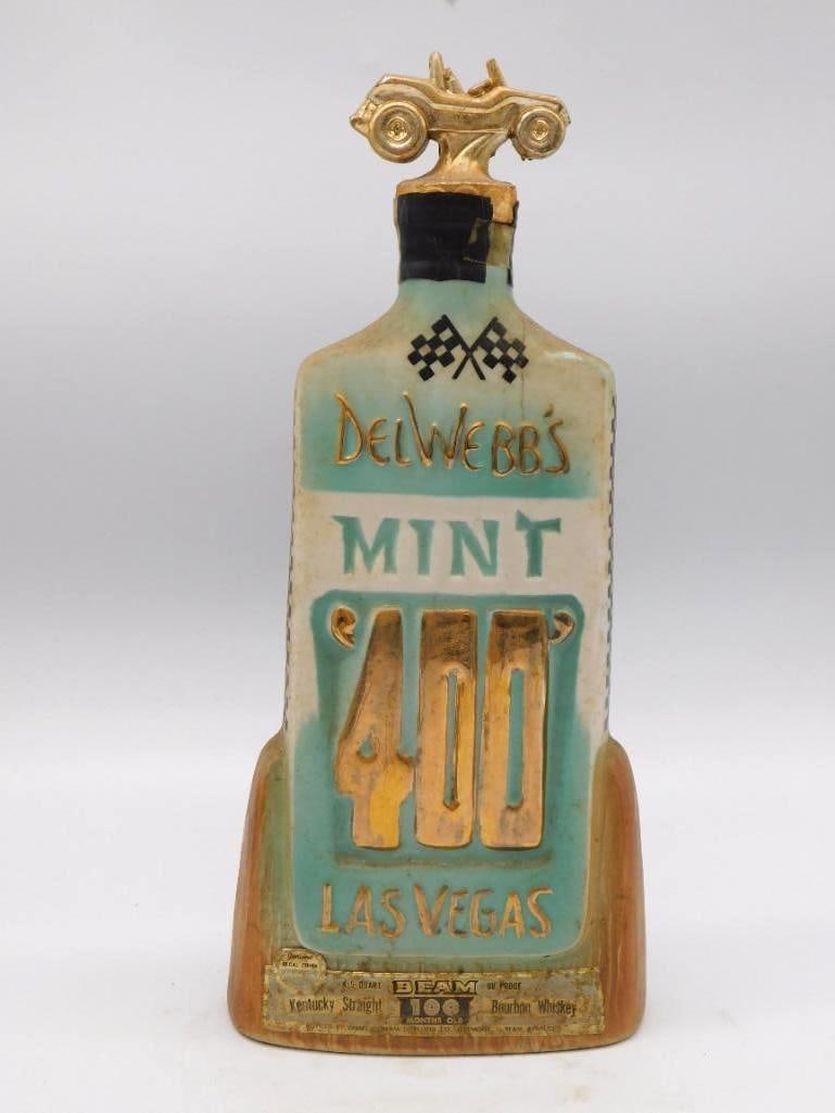 Jim Beam Del Webb's Mint 400 Desert: A Jim Beam decanter marking the 3rd Annual Del Webb's Mint 400 Desert Rally at Las Vegas, March 1970, topped with a gold-tone dune buggy in place of a plain stopper. Labeled 100 Months Old Kentucky St