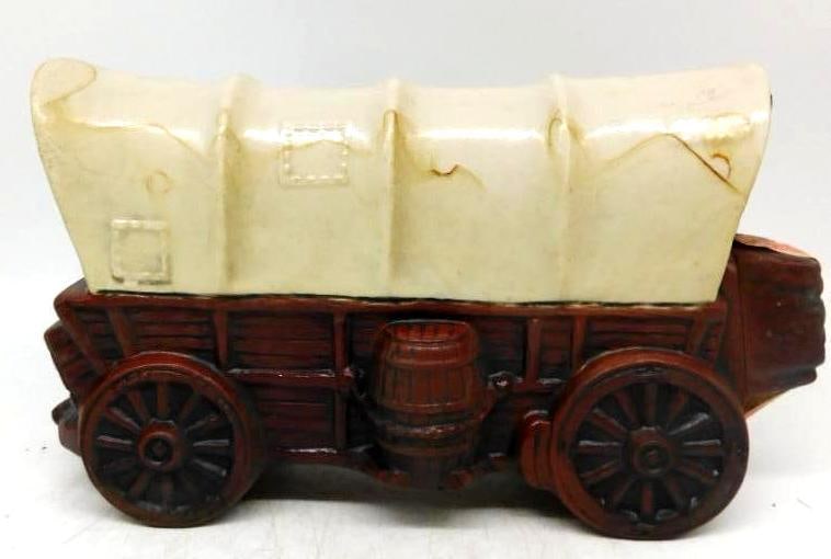 Covered Wagon Prairie Schooner Ceramic: A homespun ceramic decanter modeled as a covered wagon, its canvas top billowed above a red-brown bed with a water keg slung at the side and stout spoked wheels below. No maker's mark is visible, so