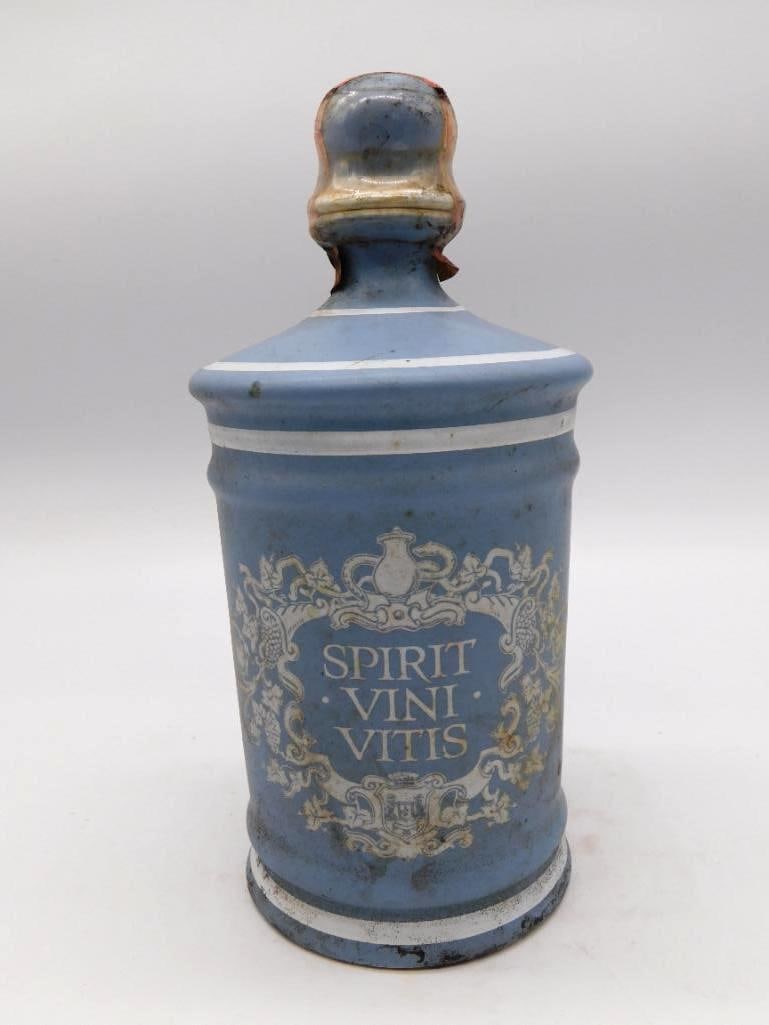 Italian Majolica Spirit Vini Vitis: An Italian glazed ceramic decanter of apothecary form in powder blue, banded in white and carrying the Latin motto "Spirit Vini Vitis" within a decorative crest. A stately shape that needs no ornament