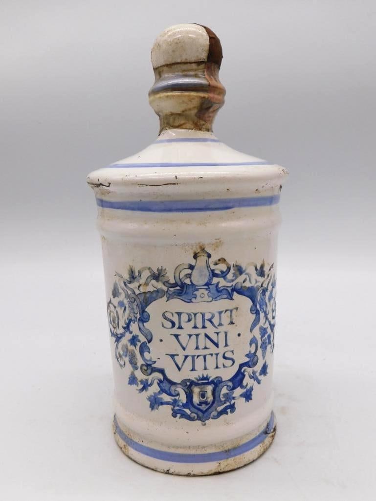 Italian Majolica Spirit Vini Vitis: An Italian glazed ceramic decanter in the apothecary manner, banded in blue and carrying the Latin motto Spirit Vini Vitis within a decorative crest. The lid shows a chip and there is a hairline