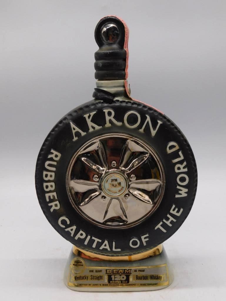 Jim Beam Colorado Centennial Ceramic: A Jim Beam ceramic decanter marking the Colorado Centennial, glazed a deep blue and cast with a relief mountain scene beneath gold lettering. The stopper takes the form of a pickaxe and is finished wi