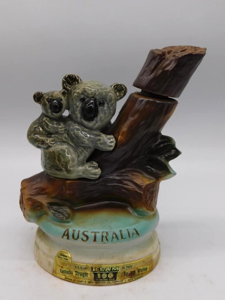 Jim Beam Australia Koala Bear Ceramic: A Jim Beam ceramic decanter modeled with two koala bears climbing a eucalyptus branch above a teal-banded base lettered Australia. A genial subject, and the mold-maker gave the little bears real