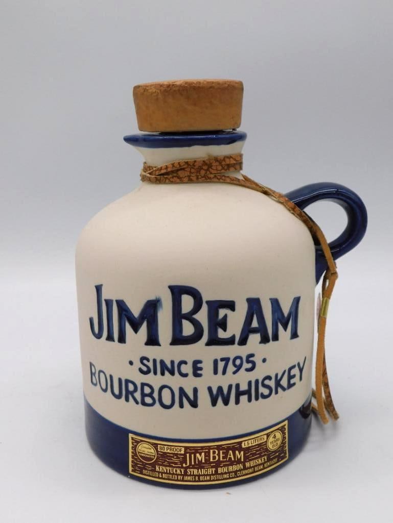 Jim Beam Since 1795 Bourbon Ceramic Jug: A trim Jim Beam jug-form decanter in cream and navy, lettered JIM BEAM SINCE 1795 BOURBON WHISKEY across the face. Its cork stopper is tied with a leather thong, homespun and agreeable. Stands