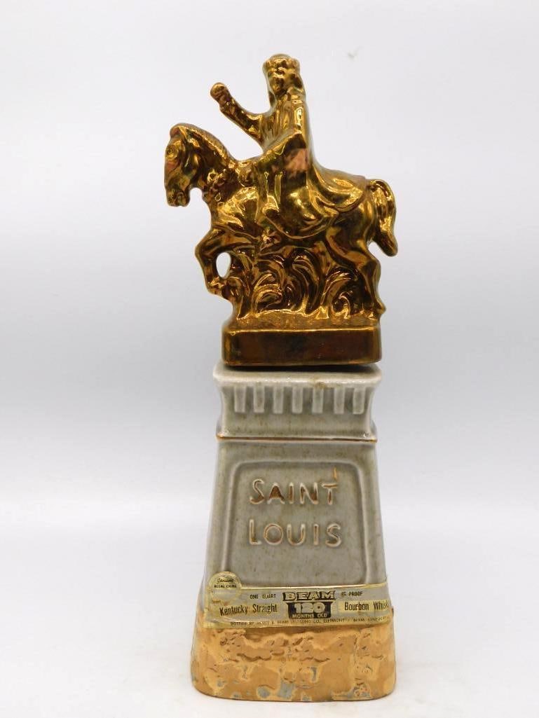Jim Beam Saint Louis Equestrian Statue: A Jim Beam Regal China decanter rendering the Saint Louis equestrian statue in bright gold luster, a mounted rider with arm raised above a rearing horse, set atop a grey stone-form pedestal lettered