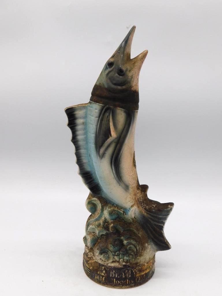 Jim Beam Leaping Marlin Sailfish Regal: A Jim Beam Regal China decanter modeled as a leaping marlin rising out of stylized waves, a lively bit of sculpture. A partial Beam and 100 Months Old label remains to the base. The surface shows
