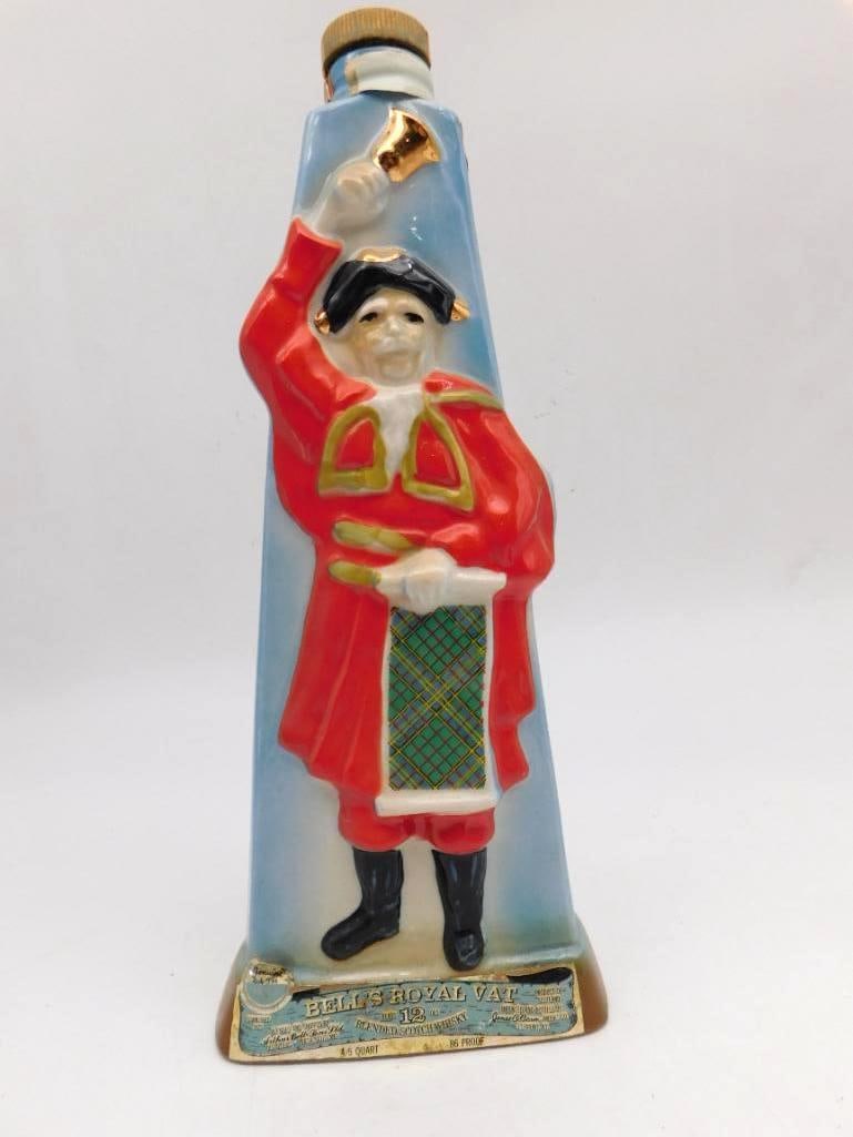 Bell's Royal Vat Scotch Whiskey Town: A Bell's Royal Vat 12 Year Old Blended Scotch Whiskey decanter modeled as a town crier in a red coat, hand bells raised and a tartan sash across his breast, with gold accents throughout. A Genuine