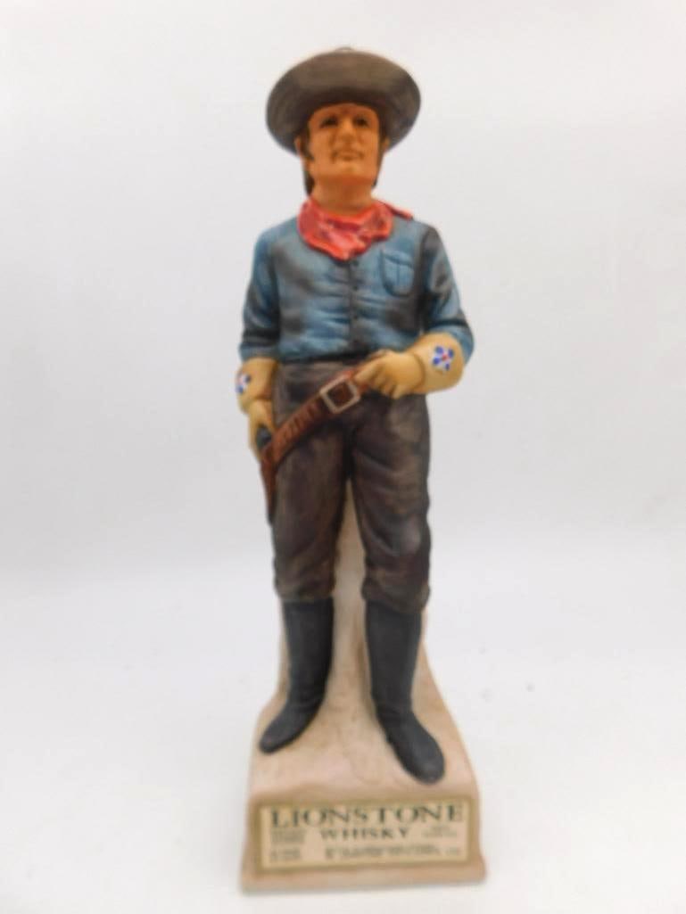 Lionstone Whiskey Cowboy with Pistol: A Lionstone Kentucky Straight Bourbon Whiskey porcelain decanter modeled as a standing cowboy in a blue shirt and red bandana, floral gauntlet gloves on his hands and a holstered pistol at his hip.