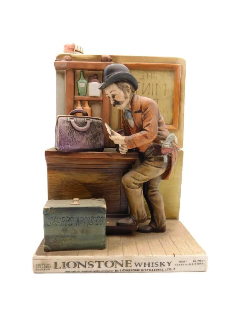 Lionstone Sharps Arms Co. Gunsmith: A Lionstone decanter rendered as a gunsmith bent to his workbench with a Sharps Arms Co. rifle case at hand. Finely hand-painted in the detailed Lionstone Western manner, and among the better