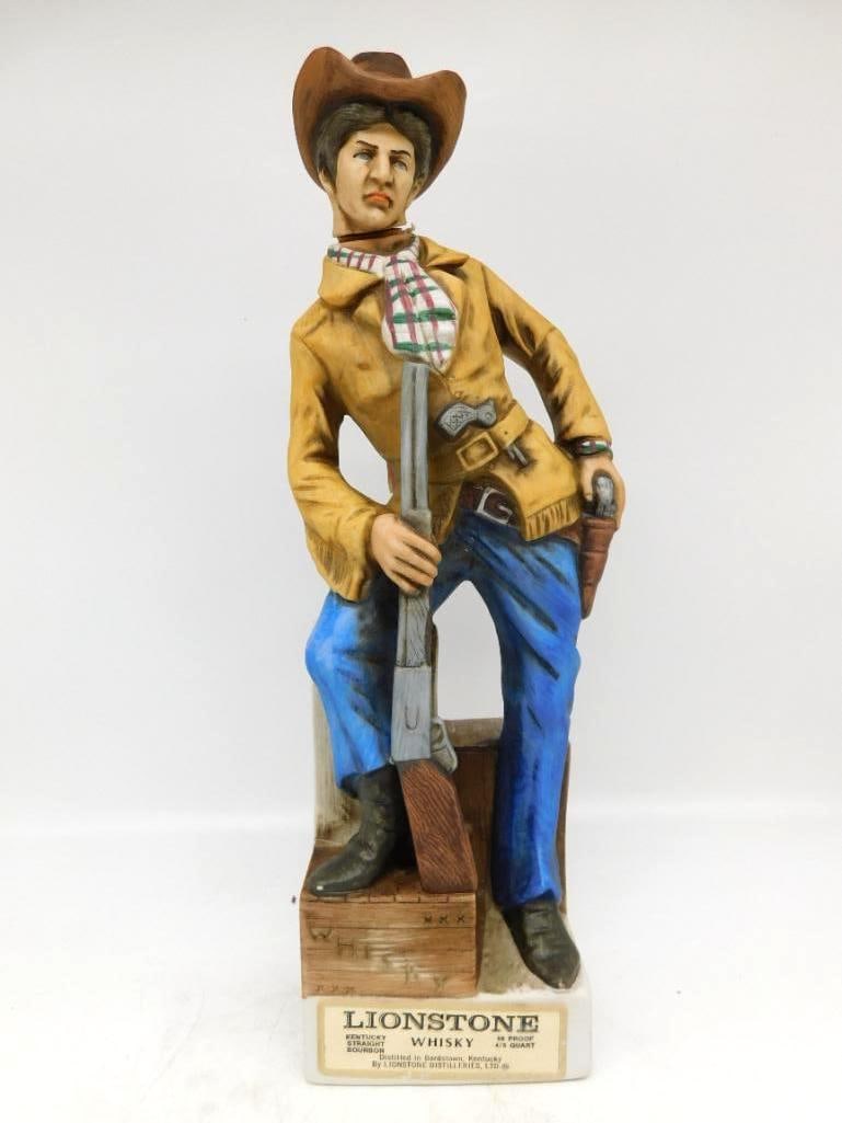 Lionstone Old West Calamity Jane: A Lionstone decanter modeled as Calamity Jane in fringed buckskin coat and blue denim, rifle in hand and pistol at her hip, leaning against a crate. The face is rendered with a shrewd eye and the