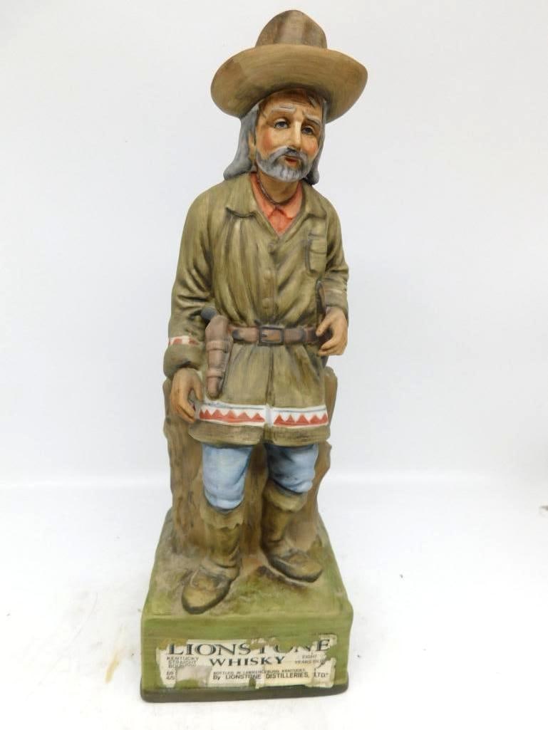 Lionstone Old West Series Squaw Man: A Lionstone decanter from the Old West Series, modeled as a frontiersman in broad-brimmed hat and buckskin shirt, a sheathed knife at his belt and a beaded blanket over one arm, standing beside a weat