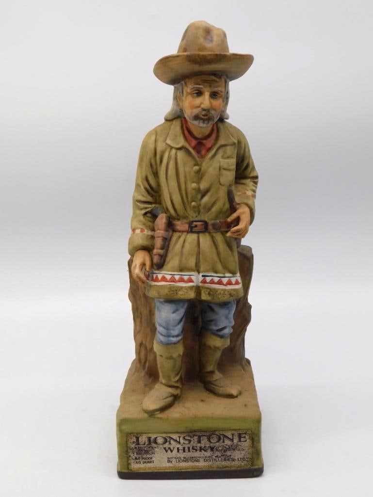 Lionstone Bearded Frontiersman Decanter: A stout Lionstone decanter modeled as a bearded frontiersman in a fringed buckskin coat, his wide-brim hat pulled low and a knife at his belt. The sculptor caught the look of a man long on the trail,