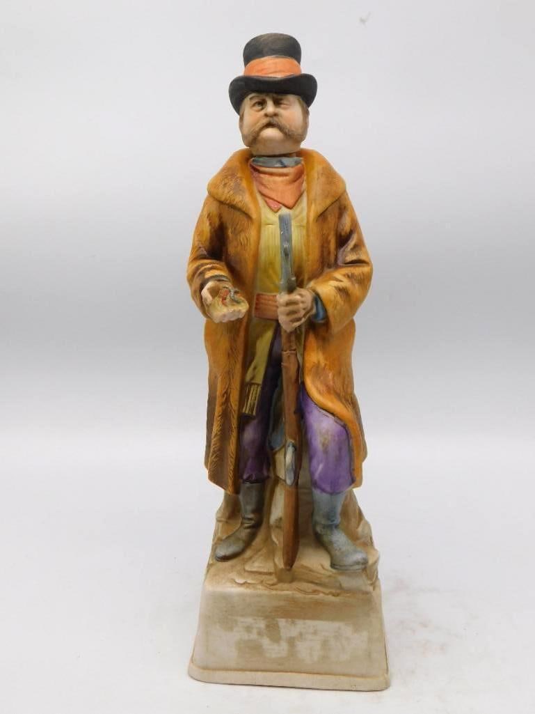Old West Renegade Trader Portrait: A decanter modeled as a frontier trader in a long coat and stovepipe hat, a rifle in one fist and a handful of cheap trinkets in the other. The face is shrewd and none too friendly, and the painter
