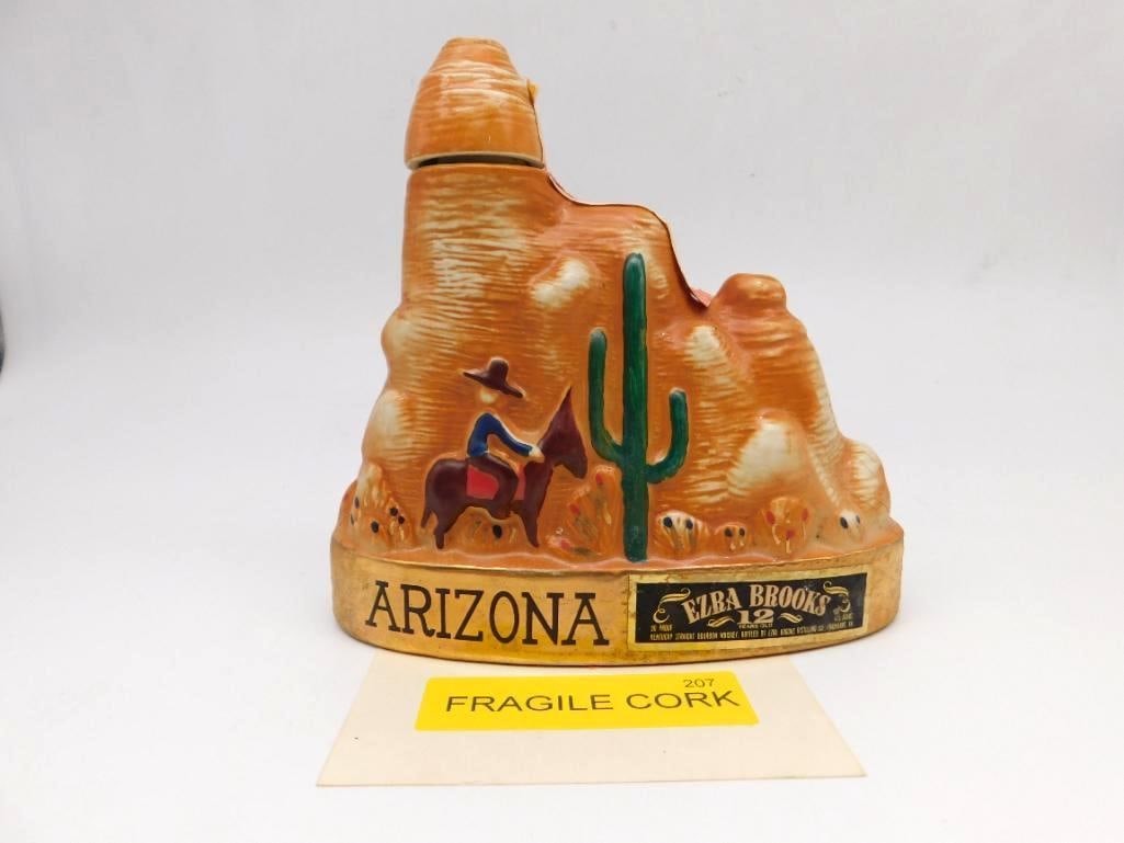 Ezra Brooks Arizona Cowboy and Saguaro: An Ezra Brooks 12-year-old decanter rendered as an Arizona desert scene, a cowboy on horseback riding past a saguaro cactus. A spirited little tableau of the Western country. Approximately 8 inches