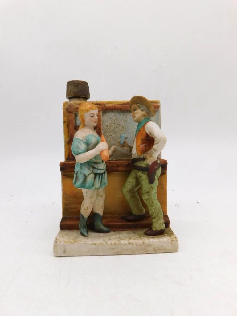 Last Chance Cologne Western Saloon Bar: A porcelain bottle from the National Porcelain Company, modeled as a saloon girl and cowboy in conversation at the bar, issued as Last Chance Cologne in the six-ounce size. The base is marked made in 