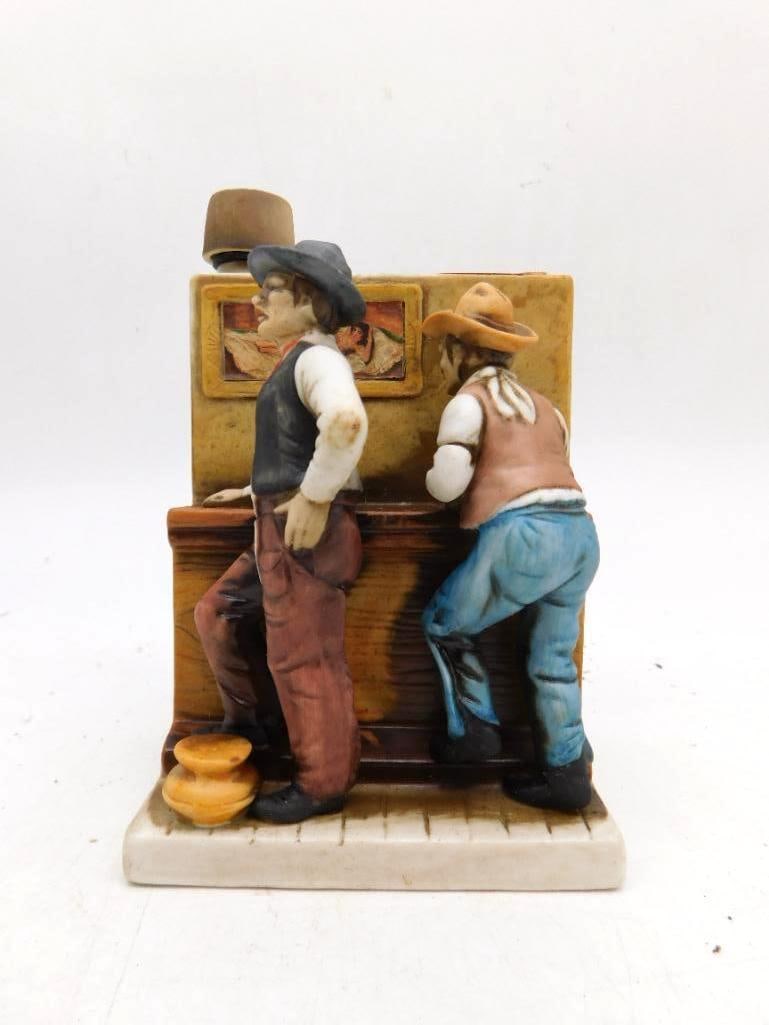 Hand-Painted Porcelain Western Decanter: A hand-painted porcelain whiskey decanter rendering two cowboys leaning at a bar, admiring a framed picture upon the wall. A genial piece of Western storytelling, similar in style to the Lionstone