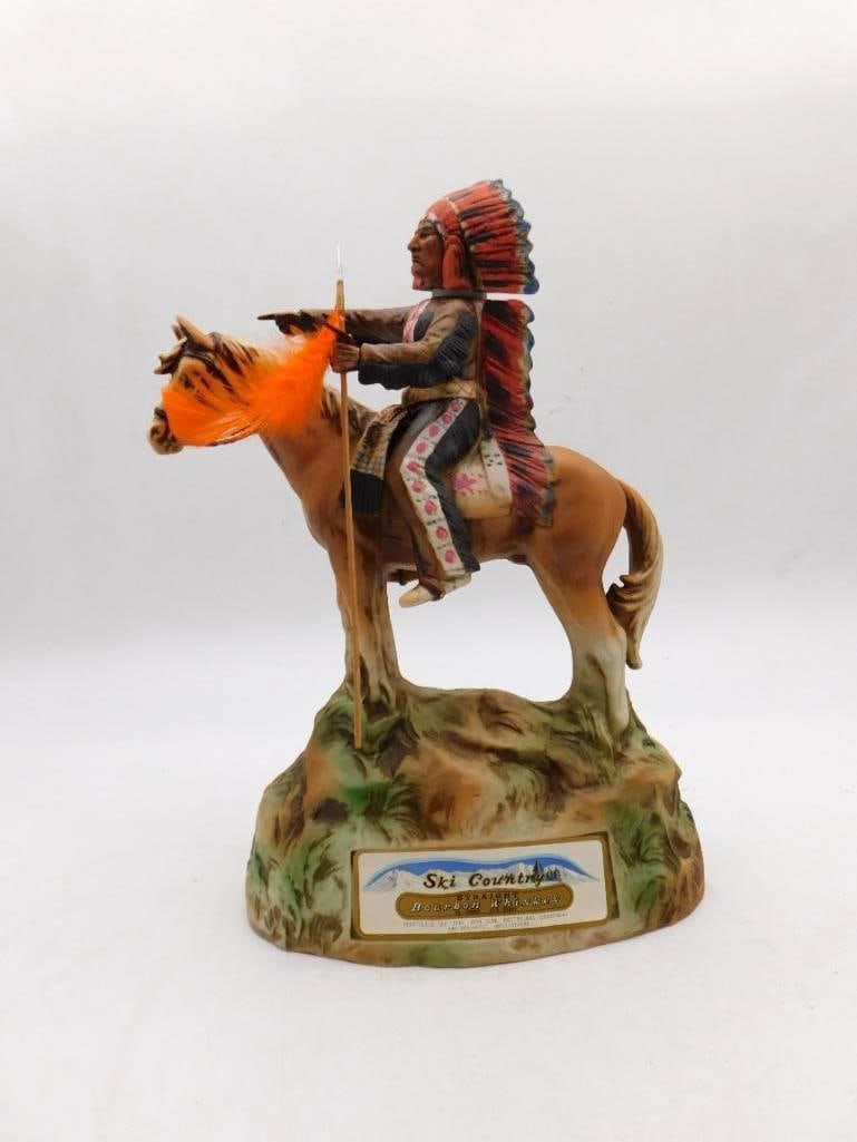 Ski Country Mounted Indian Chief: A commanding Ski Country decanter modeled as an Indian chief in full feathered war bonnet, mounted upon a standing horse and holding a lance dressed with orange plumes. The trailing bonnet and the pai