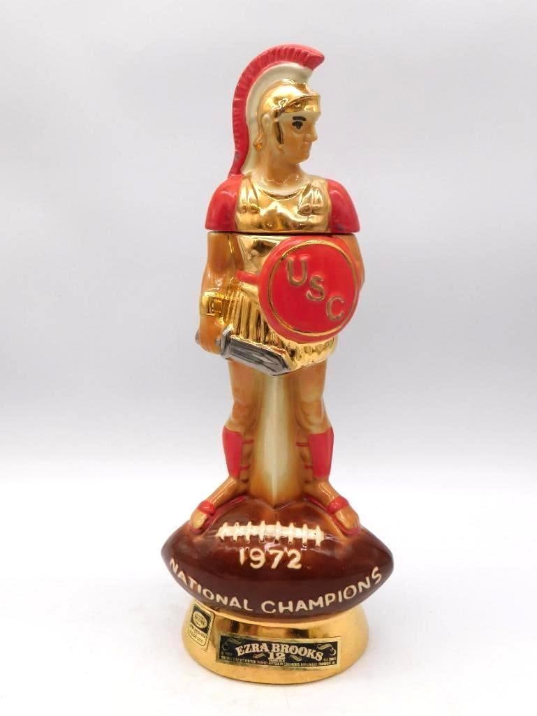 Ezra Brooks USC Trojans 1972 Natl: A commanding Ezra Brooks decanter in gold and red, modeled as the USC Trojan mascot standing upon a football base inscribed 1972 NATIONAL CHAMPIONS. The reverse carries the USC football history togeth