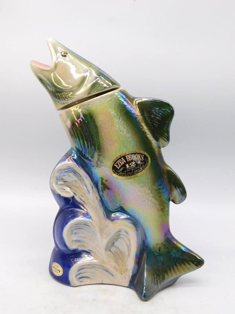Ezra Brooks Washington State King Salmon: An Ezra Brooks decanter shaped as a king salmon breaking from a blue and white curl of water, finished in a lively iridescent glaze that shifts from green to violet as it turns. The head lifts free as