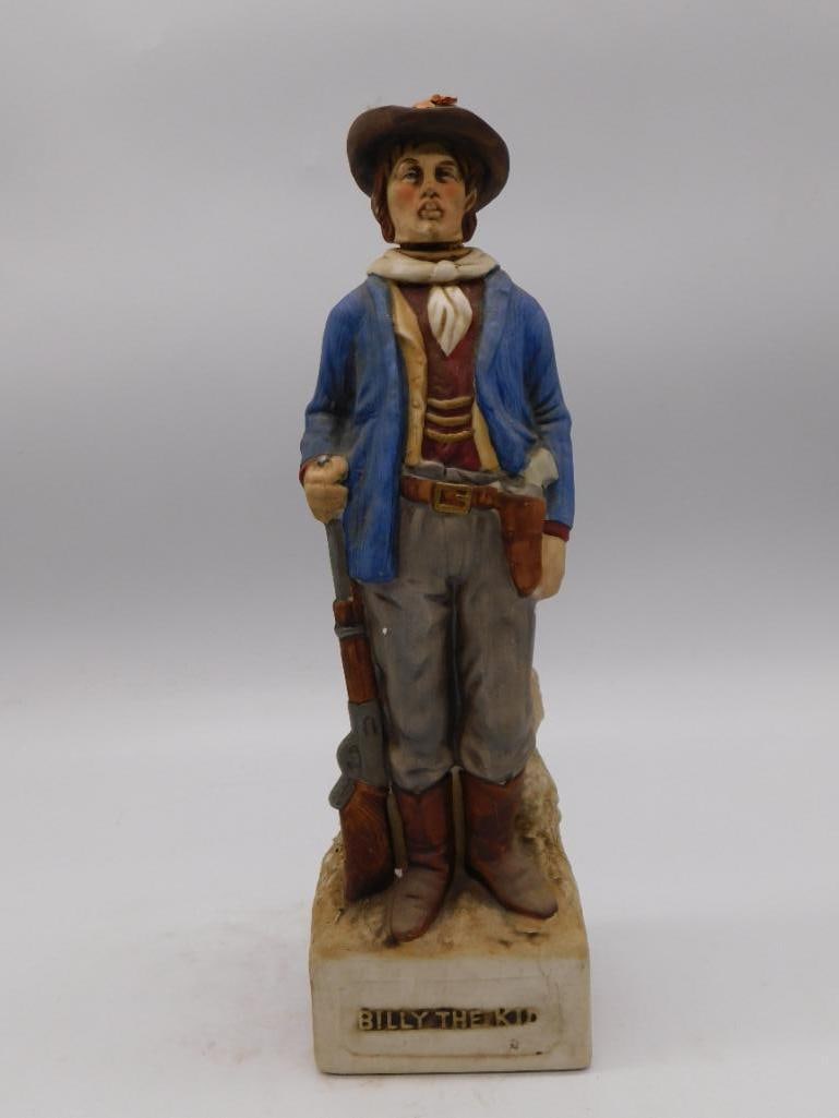 McCormick Billy the Kid Old West Outlaw: A McCormick decanter modeled as Billy the Kid, the young outlaw standing lean and watchful with a rifle at his side and a pistol on his hip. The sculptor gave him a boyish face beneath a broad brown