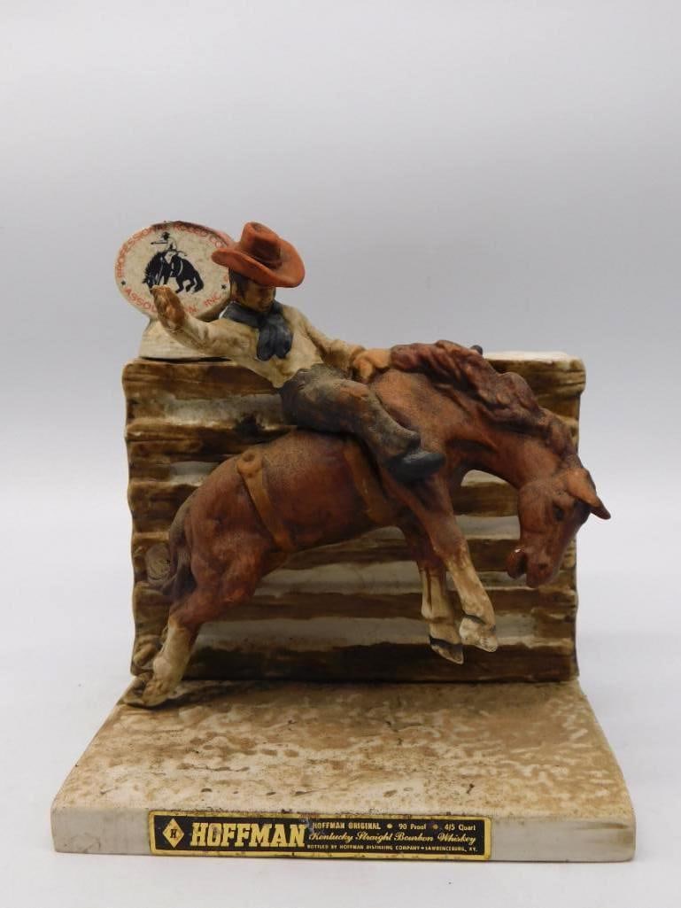 Hoffman Professional Rodeo Cowboys: A spirited Hoffman decanter modeled as a rodeo hand riding a bucking bronc out of the chute, hat up and one arm high, the emblem of the Professional Rodeo Cowboys Association behind him. The reverse b