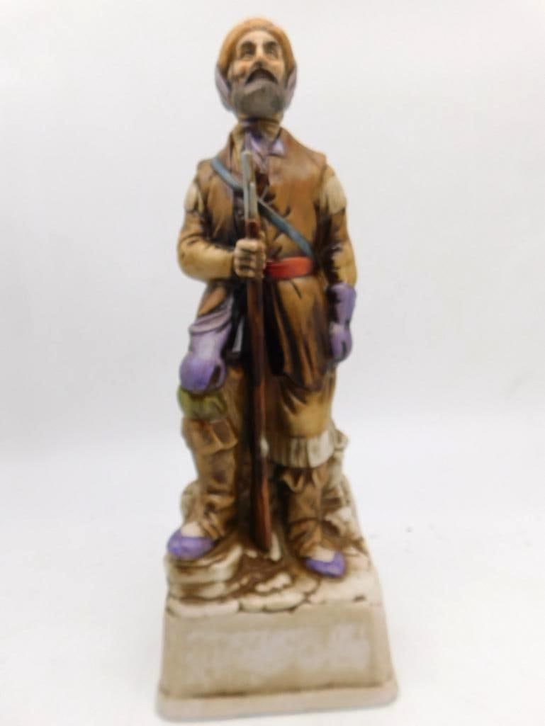 Bitterroot Sculptured Porcelain 1969: An Original Bitterroot Sculptured Porcelain decanter of 1969, modeled as a bearded frontiersman in buckskin holding a musket, a leather pouch at his side. An Oklahoma tax stamp is visible upon the