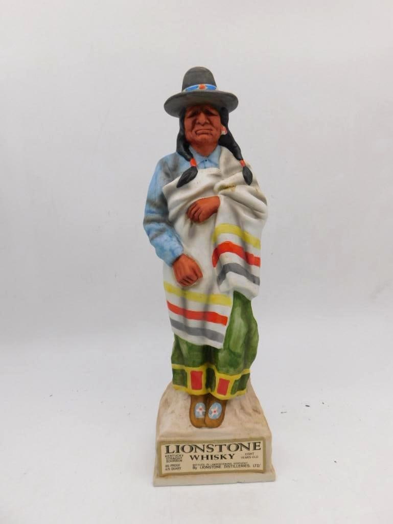 Lionstone Whiskey Native American in: A Lionstone Kentucky Straight Bourbon Whiskey porcelain decanter portraying a Native American man wrapped in a striped trade blanket beneath a wide-brimmed hat, upon a rock-form base with descriptive