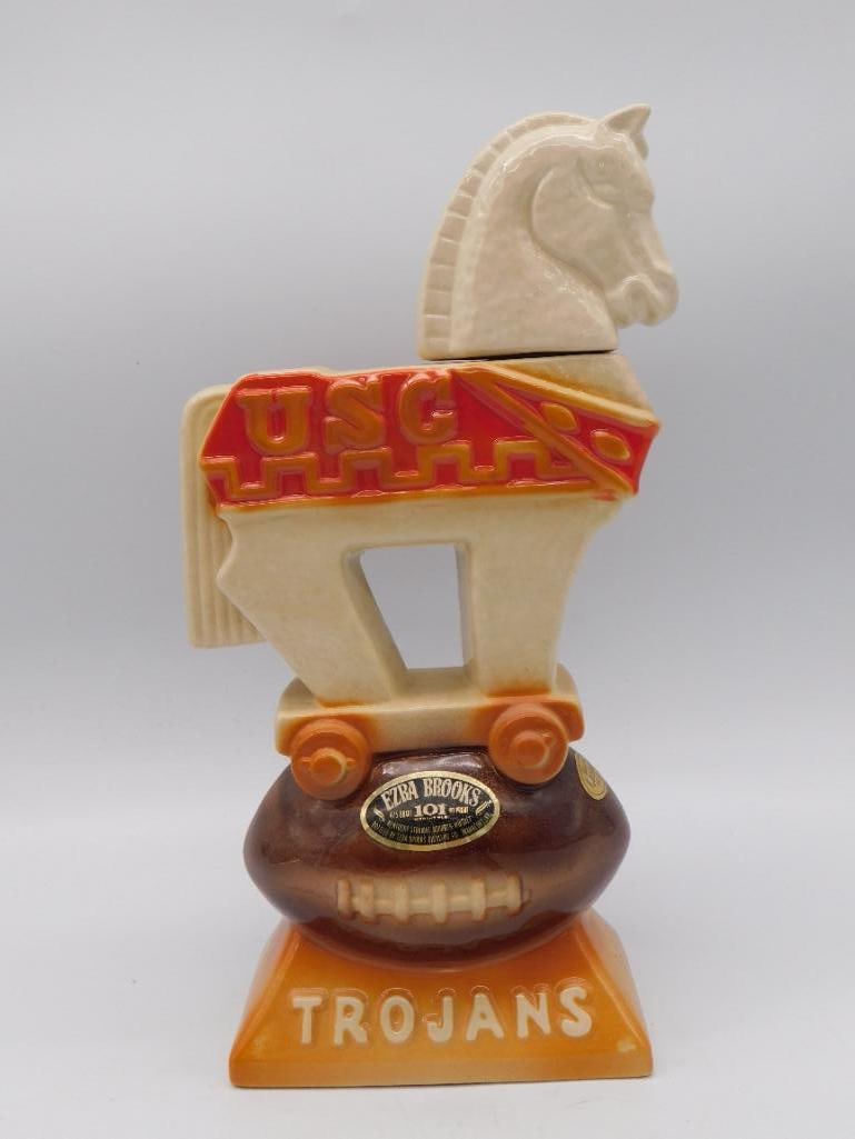 Ezra Brooks USC Trojans Mascot Horse: A spirited Ezra Brooks decanter modeled as the USC Trojans mascot horse on wheels, set upon a football-form base lettered Trojans. The mold-maker gave the little horse a lively step, and the painter