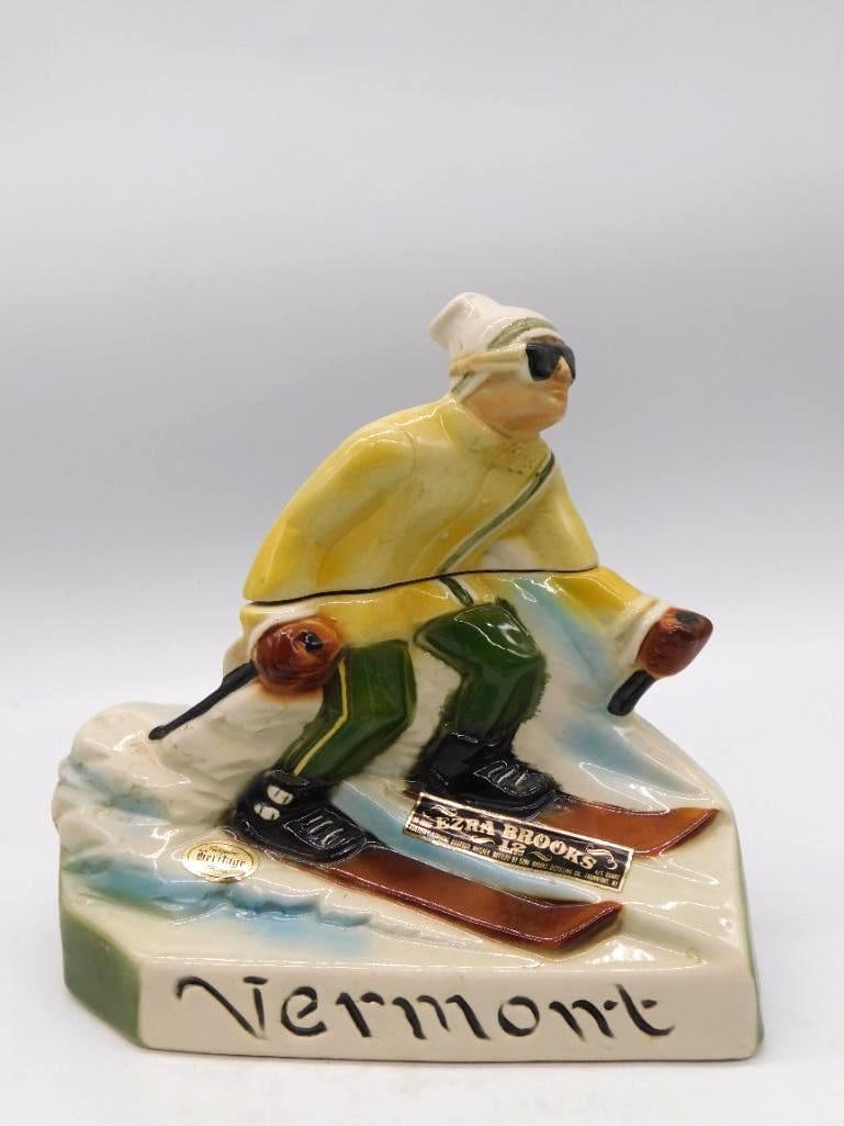 Ezra Brooks Vermont Skier Ceramic: An Ezra Brooks ceramic decanter sculpted as a downhill skier in a yellow jacket, the base marked Vermont. A lively piece of winter sport, well modeled for its size. Approximately 8.5 inches long as ph