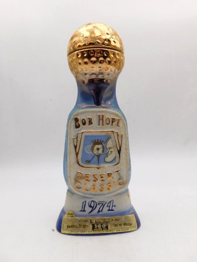 Jim Beam Bob Hope Desert Classic 1974: A Jim Beam Regal China decanter marking the 1974 Bob Hope Desert Classic golf tournament, topped with a textured gold golf-ball finial. The original Beam gold neck label is present, with typical light