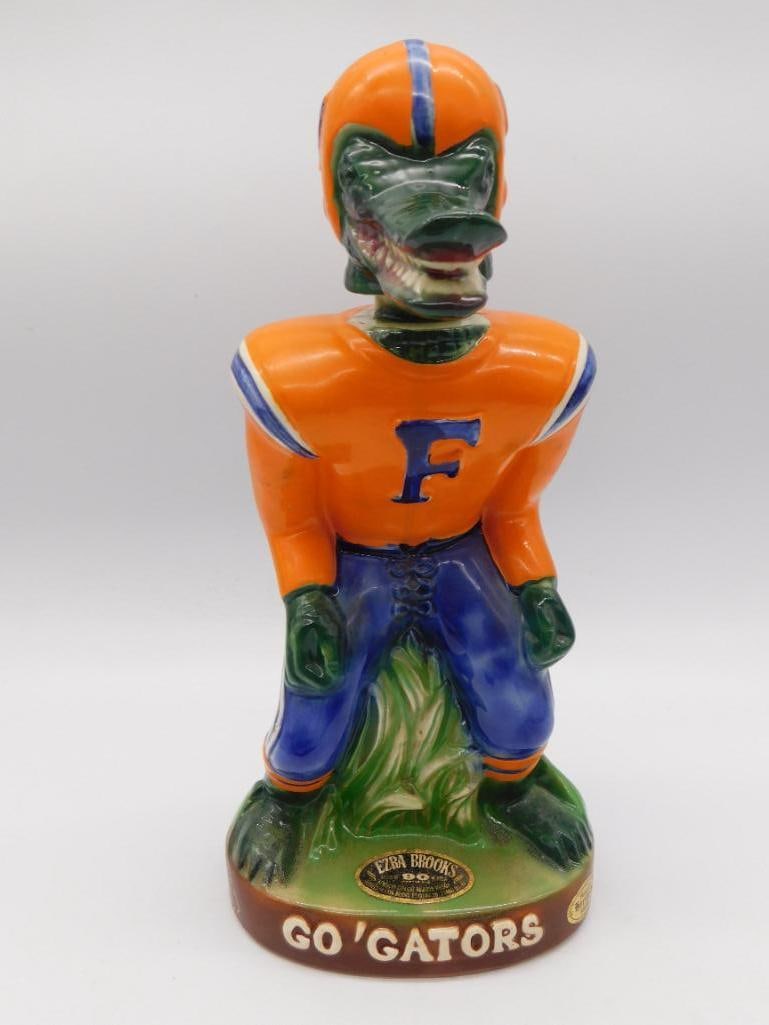Ezra Brooks Florida Gators Football: A spirited Ezra Brooks whiskey decanter modeled as a University of Florida Gators football player, suited out in orange and blue beneath a gator-head helmet. The mold-maker gave him a stance with