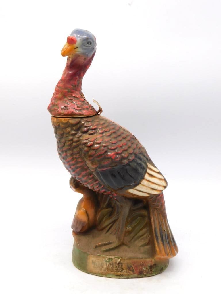 Wild Turkey Standing Tom Turkey Ceramic: A Wild Turkey decanter rendered as a wild tom perched upon a stump, neck stretched and wattles bright. The molding of the feathers is workmanlike and lively, though the paint has thinned across the