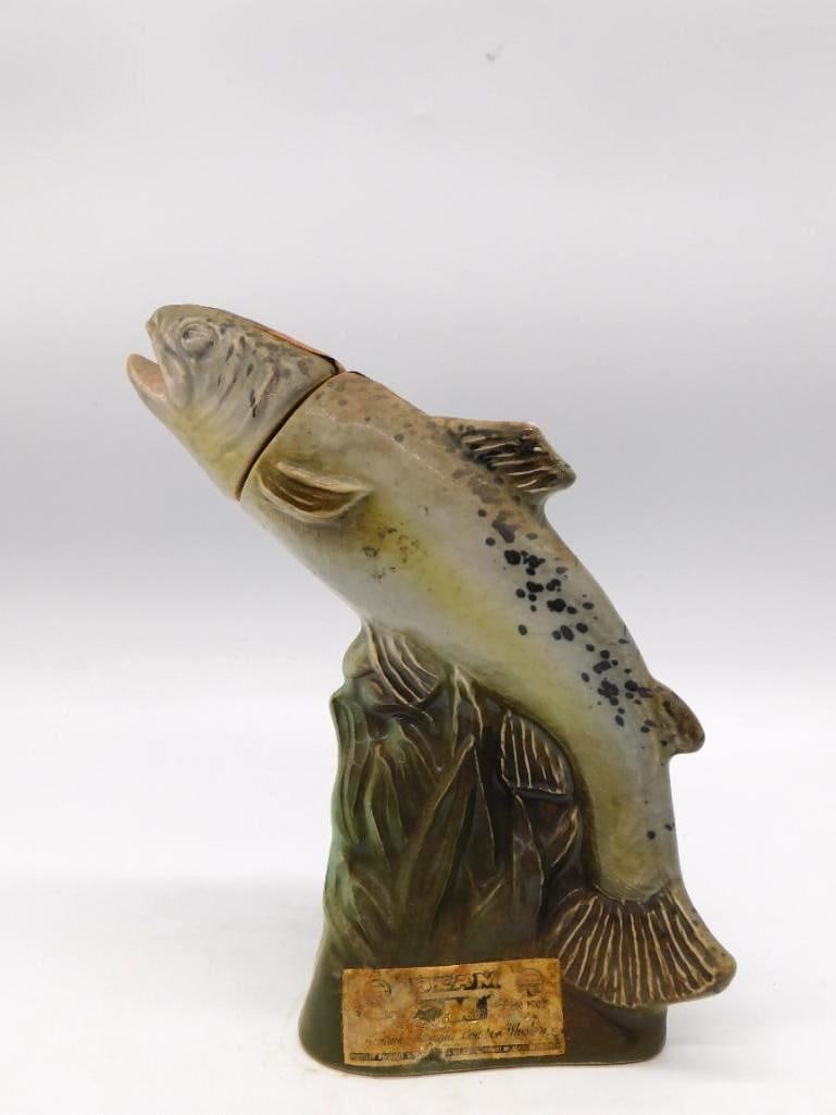 Jim Beam Speckled Trout Ceramic Decanter: A ceramic Jim Beam decanter in the form of a leaping speckled trout, the spotted flank rendered with a lively hand. Finished with a gold presidential-seal style stopper and carrying the Beam Kentucky