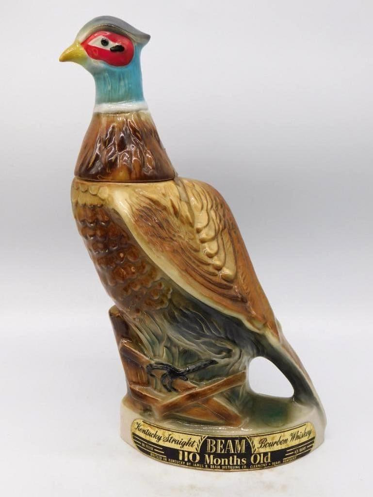 Jim Beam Ring-Necked Pheasant Decanter: A handsome Jim Beam decanter modeled as a ring-necked pheasant perched upon a rail, head turned and long tail sweeping low. The glazing is lively across the barred brown plumage, and the scarlet face