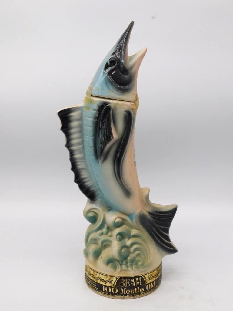Jim Beam Marlin Game Fish Decanter, 100: A Jim Beam decanter modeled as a marlin leaping clear of a curling wave, bill up and sail fin raised. The airbrush work moves from pale blue to deep black along the back with an agreeable, watery soft