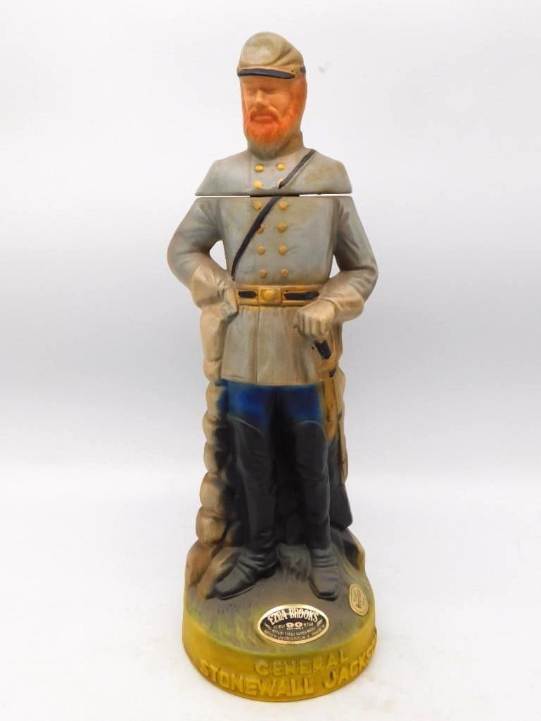 Ezra Brooks General Stonewall Jackson: A sober Ezra Brooks decanter modeled as General Stonewall Jackson, standing resolute in a gray field coat with sash and saber beside a stone wall, the name lettered in gold across the base. The