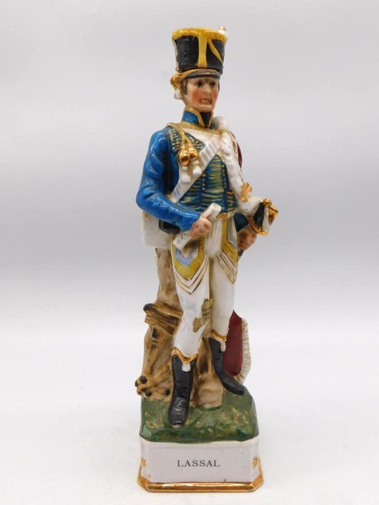 Grenadier Lassal Napoleonic French: A ceramic decanter sculpted as Lassal, a Napoleonic-era French officer in a blue coat with gold and white trim, standing upon a green grass-textured base with a small cannon at his side. A gallant