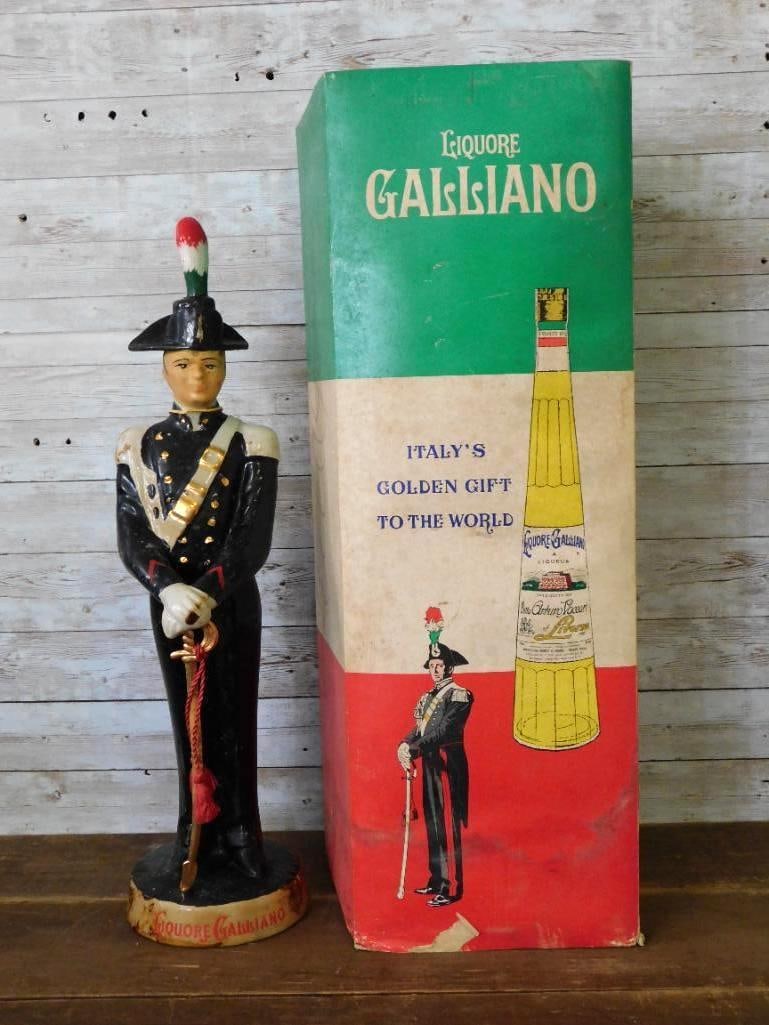 Liquore Galliano Italian Carabiniere: A tall Liquore Galliano decanter modeled as an Italian carabiniere at attention, sword held in his gloved hands and a red and green plume rising from his bicorne. Gold buttons and braid stand out
