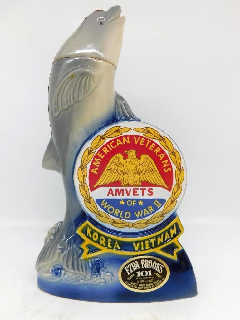 Ezra Brooks AMVETS Dolphin 1974: An Ezra Brooks decanter modeled as a dolphin leaping from the wave, its flank bearing the seal of the American Veterans of World War II with Korea and Vietnam on the banner below. The reverse is