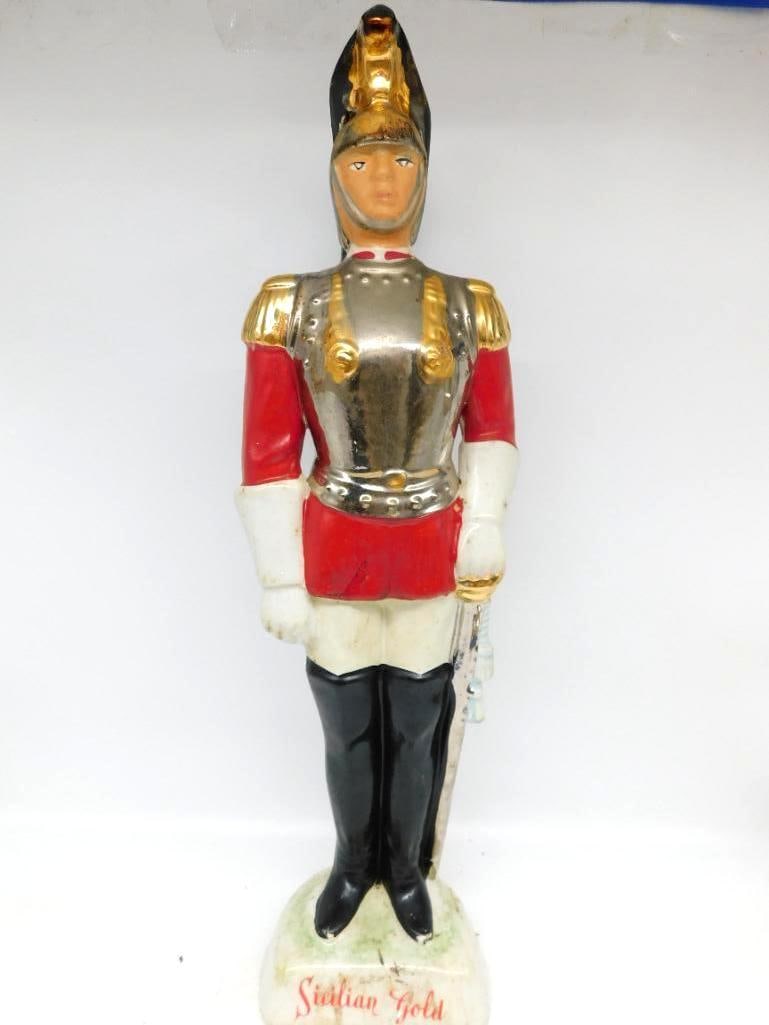 Sicilian Gold Mandorcrema Italian Royal: A stately ceramic decanter modeled as an Italian Royal Guard standing at attention in scarlet tunic and silver cuirass, with gold epaulettes, plumed helmet and a sword at his side. The modeling is wor