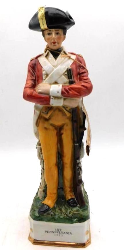 Grenadier 1st Pennsylvania 1775: A handsome Grenadier decanter modeled as a soldier of the 1st Pennsylvania, red coat and buff breeches, crossbelts white and musket grounded at his side. The tricorn lifts away as the stopper and the