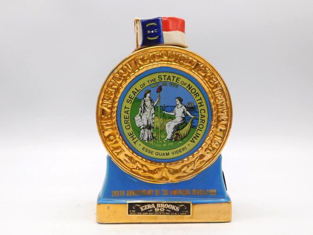 Ezra Brooks North Carolina Bicentennial: A round ceramic decanter from Ezra Brooks bearing the Great Seal of the State of North Carolina in blue and gold, struck for the 200th Anniversary of the American Revolution. A North Carolina state