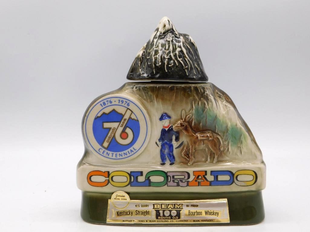 Jim Beam Colorado Centennial 1876-1976: A ceramic decanter from Jim Beam shaped as a Colorado mountain, struck for the Centennial of 1876-1976. A prospector and his burro are modeled at the foot of the slope, and a snow-capped peak serves a