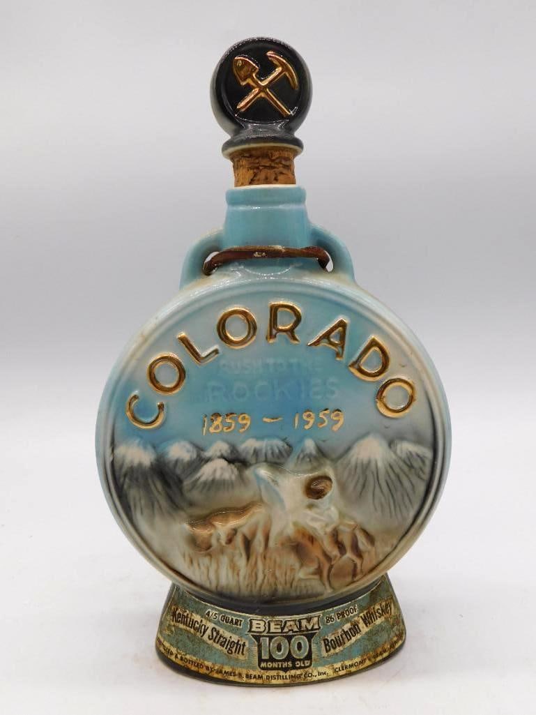 Jim Beam Colorado Gateway to the Rockies: A Jim Beam ceramic decanter marking Colorado's centennial, 1859-1959, molded with a mountain scene and lettered in gold, fitted with a black pickaxe-motif stopper. A trim and handsome tribute to the