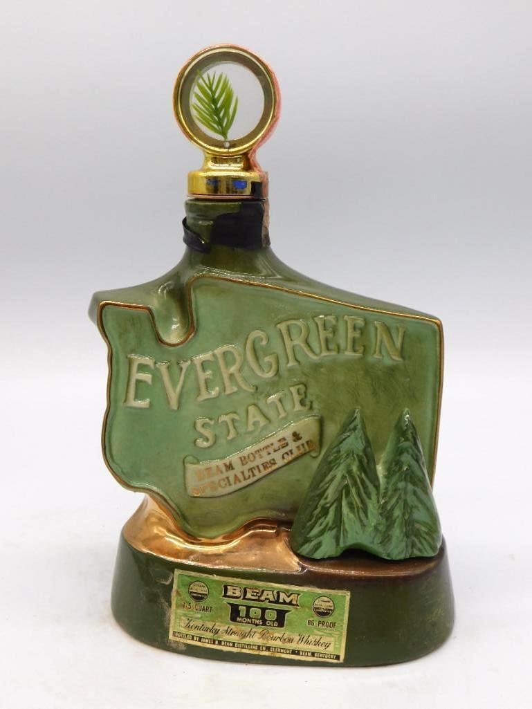Jim Beam Evergreen State Washington: A green ceramic Jim Beam decanter cut to the shape of the state of Washington and lettered Evergreen State. The stopper cap is molded as a pine tree, and the Beam Bottle and Specialty Club paper