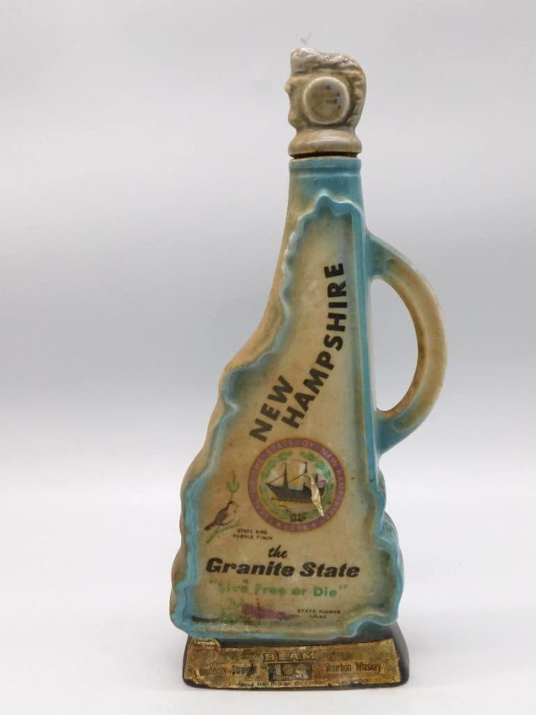 Jim Beam New Hampshire Granite State: A Jim Beam ceramic decanter cut to the outline of New Hampshire with a jug handle, bearing the state seal, the state bird and flower, and the motto Live Free or Die. Labeled Beam Kentucky Straight