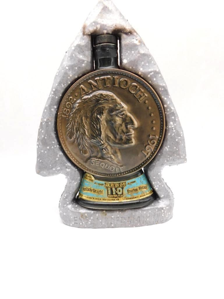 Jim Beam Antioch Illinois Diamond: A Jim Beam Regal China decanter in an arrowhead form with a stone-look surface, set with a bronze-tone medallion bearing a Native American profile and the legend "Antioch, Sequoit, 1892-1967."